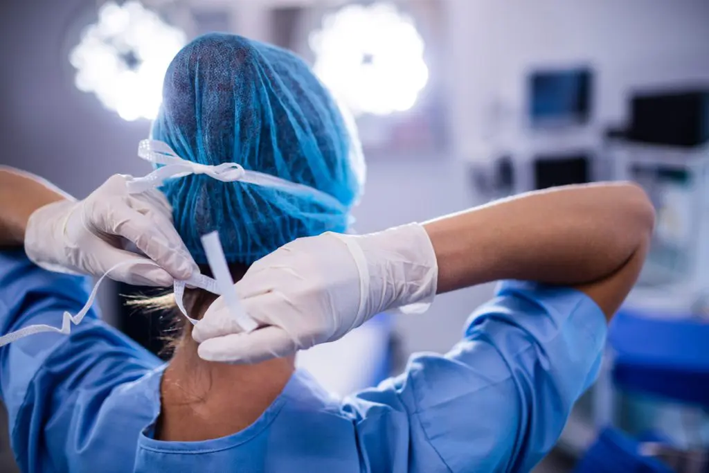 Female nurse tying surgical mask in operation theater