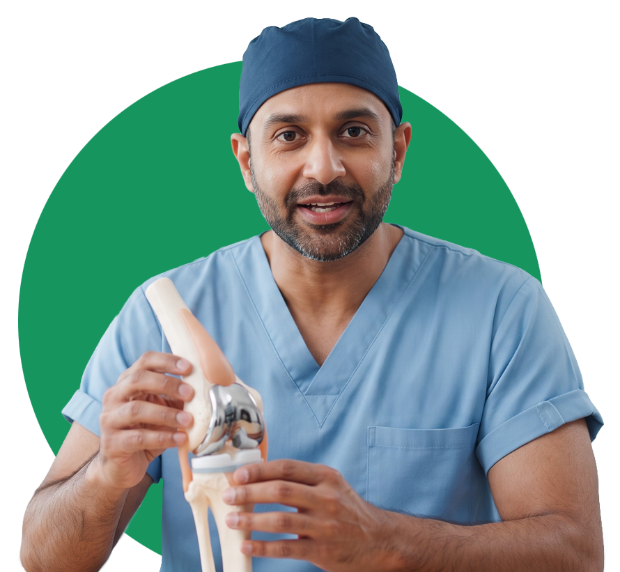 A surgeon in blue scrubs and a cap holds a model of a human knee joint with a metallic implant.