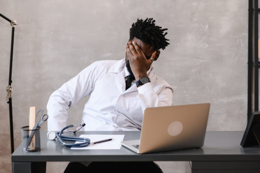 doctor looking frustrated holding head in his hand