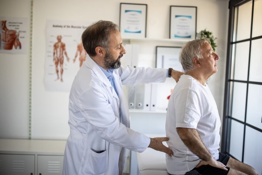 doctor checking an elderly man's spine