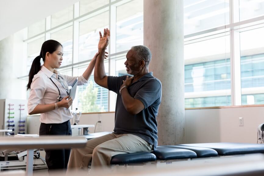 doctor stretching a patient's shoulder while he sits