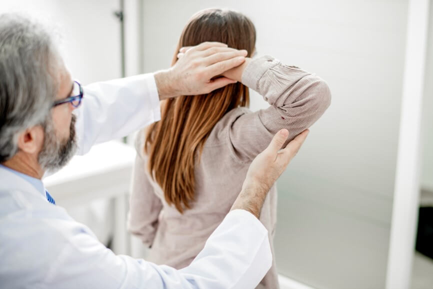 doctor stretching patient's shoulder from behind