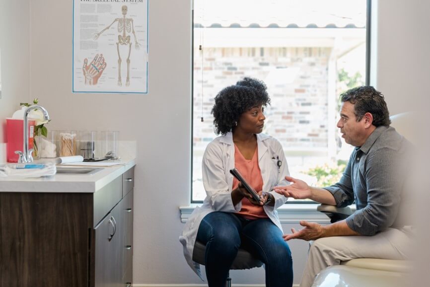Doctor and patient in a clinic room reviewing iPad