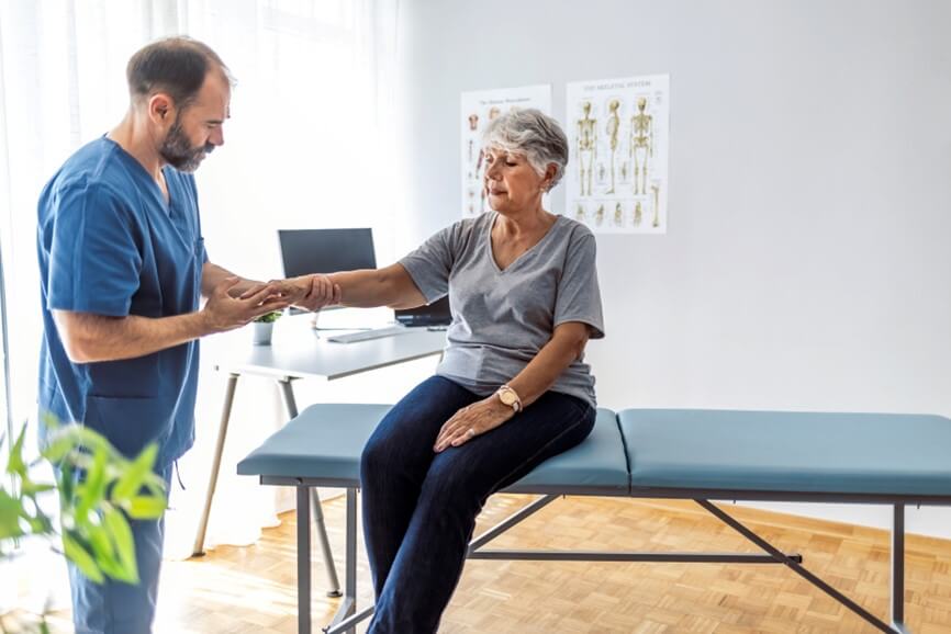 doctor examining arm of patient while she sits in room
