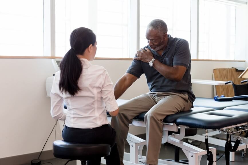 doctor examining patient's arm while both are sitting