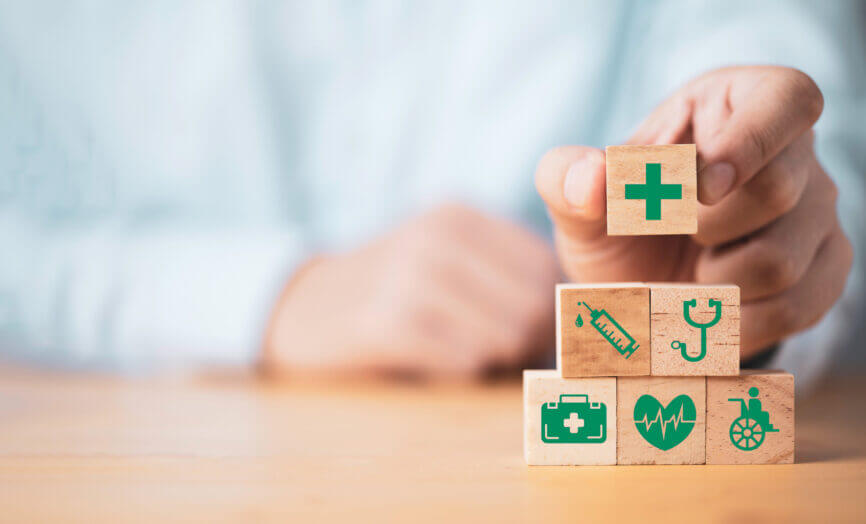 an unrecognizable person assembling building blocks with medical icons on them