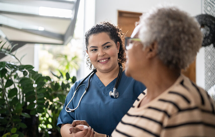 white healthcare professional holding the hand of an African American patient
